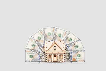 Wooden house model, dollar bills: Investing in real estate and securing a mortgage fund.