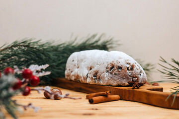 Christmas stolen in powdered sugar on a light background with pine branches and tangerines. Traditional Christmas delicacies. Front view