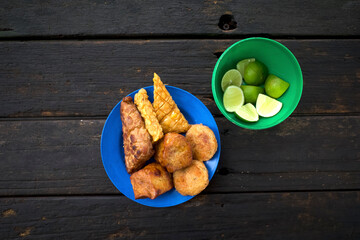 Various traditional fried food, Gorengan from Indonesia, on a blue plastic plate and sliced lemon