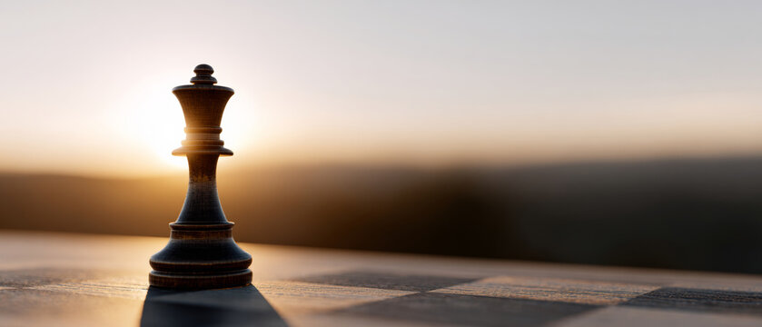 Close-up of a black king chess piece on a chessboard with warm sunlight and blurred background during sunset