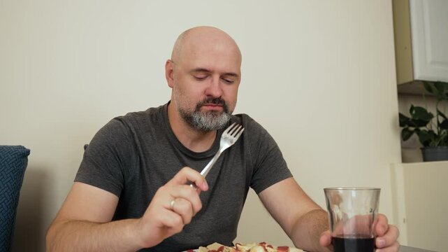 Man licking fork with dumpling and making funny expression while eating. Person tasting dumpling in humorous way and touching fork with tongue. Scene showing man eating dumplings playfully and licking