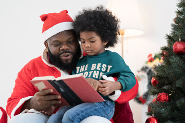 African American family reading book together at home. African American father and baby reading...
