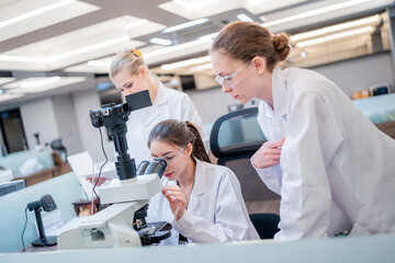 Students conduct research while using a microscope in a modern laboratory setting during a science class