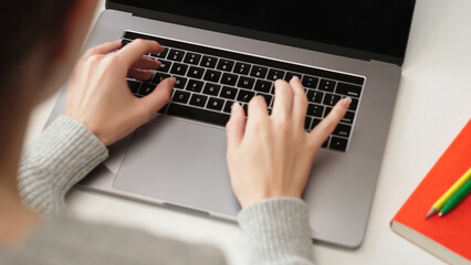 Over the shoulder view of woman typing on laptop keyboard, focusing on hands and productivity, suitable for business, remote work, and study concepts.