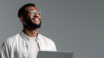 Focused Vision: Portrait of a person, radiating positivity and purpose, holding a laptop, gaze directed skyward, against a plain backdrop.
