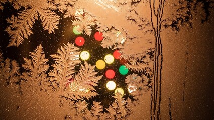 Magical frost patterns frame warm holiday bokeh lights outside