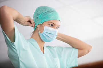 female nurse puts on a surgical mask