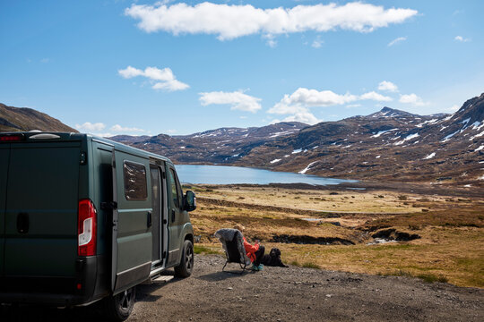 Man looking at mountains while sitting next to van during road trip