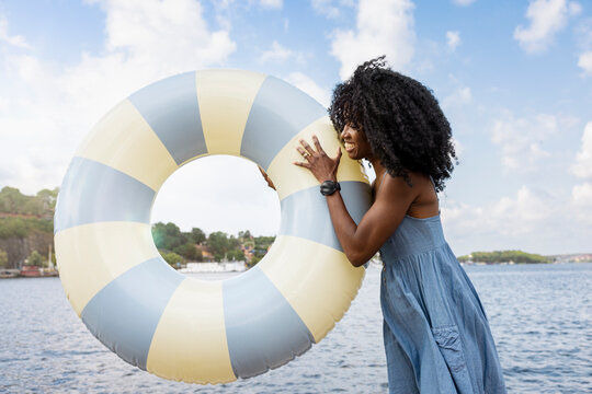 Young female tourist holding swimming float near river