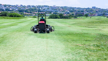 Obraz premium Golf Course Hole Maintenance Team Green Cutting Machine for Rough and Fairways