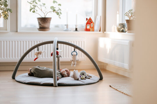 Baby boy with pacifier lying down in baby gym