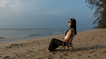 Woman relaxing on a beach chair, enjoying the calm sea and peaceful afternoon light.