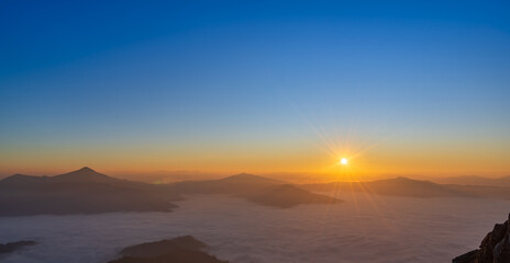 Beautiful sunrise above soft mist and mountain layers.