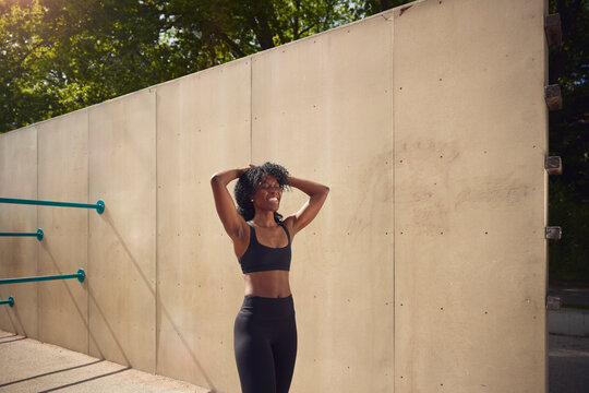 Happy woman with head in hands standing near wall at park