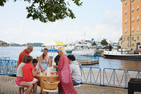 Family members eating while enjoying picnic at riverbank