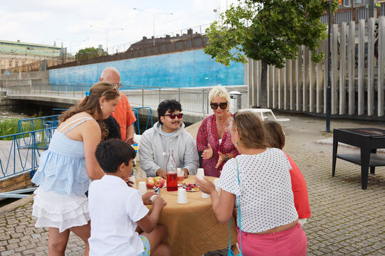 Male and female family friends eating snacks while sitting at table