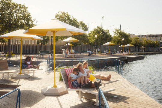 Mother and son spending leisure time with each other while sitting on deck chair at sunny day