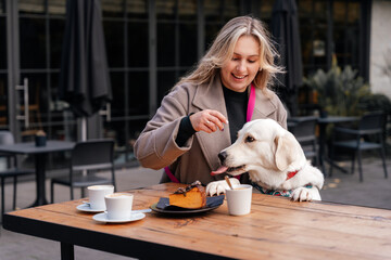 Pet-friendly coffee break with golden retriever as owner offers dog treats at outdoor cafe table