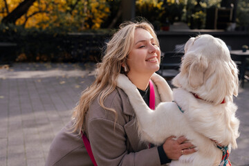 Portrait of smiling woman hugging golden retriever outdoors in autumn