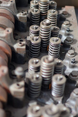 ​A close-up shot of weathered, teal-painted engine pulleys and belts, showing rust, texture, and remnants of red paint in bright sunlight.
