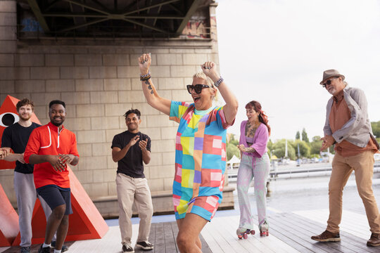 Carefree mature woman freestyle dancing around friends on pier