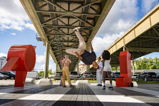 Mid-air shot of young man doing somersault on platform under bridge