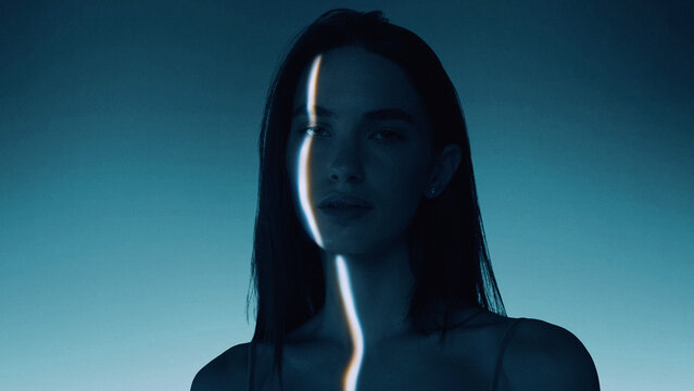 Moody artwork of female portrait divided by vertical glowing energy streak. Concept of skincare analysis, facial symmetry mapping, beauty diagnostics and digital enhancement.