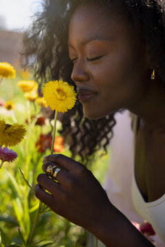 Young woman smelling chrysanthemum flower with eyes closed
