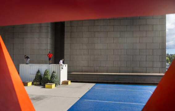 Distant view of male friends on cargo container against brick wall
