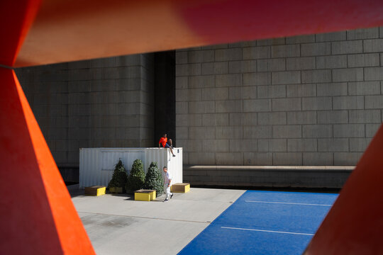 Distant view of male friends spending leisure time on platform near cargo container