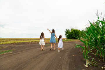 Mother with children playing in the countryside on the field. Family walk in nature.