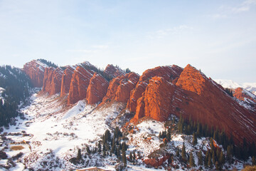 Panoramic view of the Seven Bulls red sandstone rock formations dusted with snow in the Jeti-Oguz valley