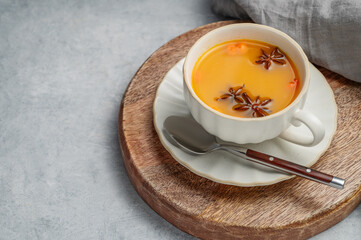 Sea buckthorn herbal tea in a cup on a wooden board on a light background