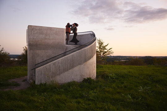 Happy friends dancing together while standing on steps against sky
