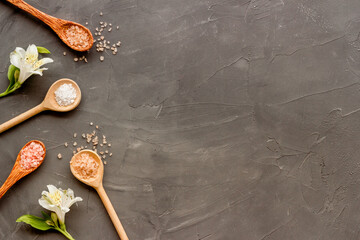 Fototapeta na wymiar Beauty spa therapy cosmetics and wellness flat lay - sea salt in many spoons with flowers, top view