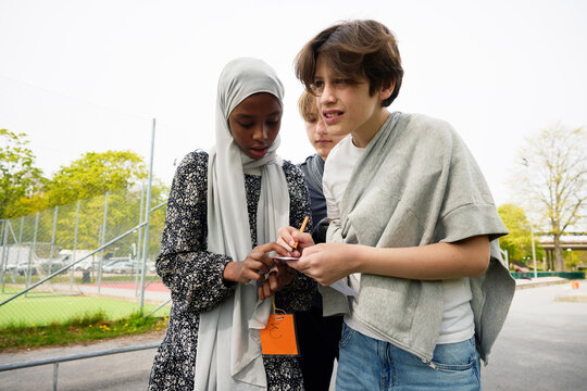 Group of students assisting each other while playing treasure hunt in school campus