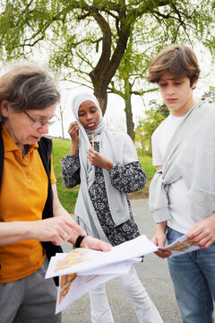 Senior teacher examining treasure maps with students outdoors
