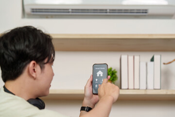 Smart Home. Young man controlling devices with smartphone.
