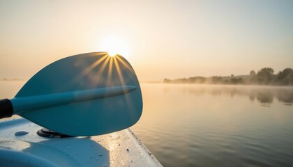 Paddle resting on boat with sunrise reflecting on calm lake  