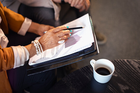 High angle view of businesswoman's hand holding pencil on data document near coffee cup in office