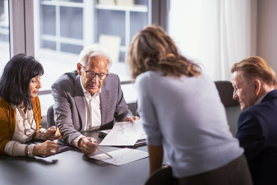 Senior businessman discussing progress report with colleagues during meeting in office board room