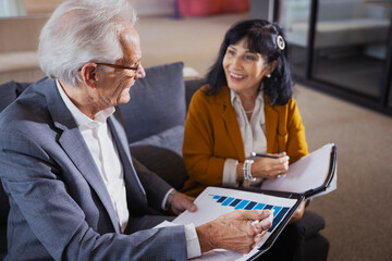 Senior businessman discussing bar graph report with female colleague while working in office