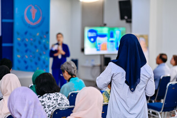 Rear view of a questioner at an event , with a blurred background