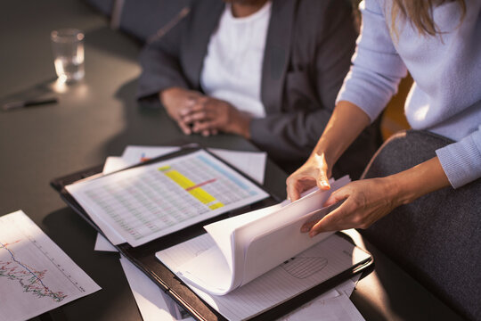 High angle midsection of businesswoman going through papers in file folder at office meeting