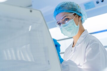 A healthcare worker in a lab coat and protective gear looks closely at samples in a clinical environment. The setting is bright and organized, focusing on safety and accuracy.