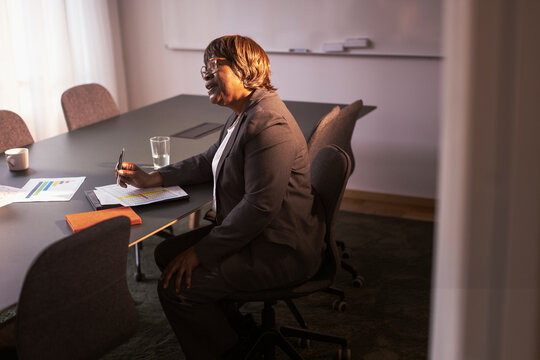 Mature female business expert sitting with documents in office meeting at board room