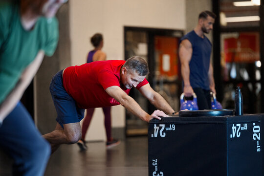 Persistent man pushing heavy box while exercising in gym