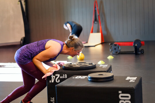 Persistent woman pushing heavy box while doing strength training in gym