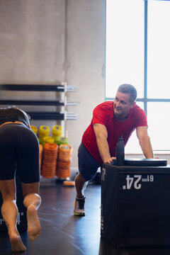 Active man pushing heavy box while exercising in gym