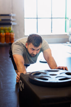 High angle view of enduring man pushing heavy box while working out in gym